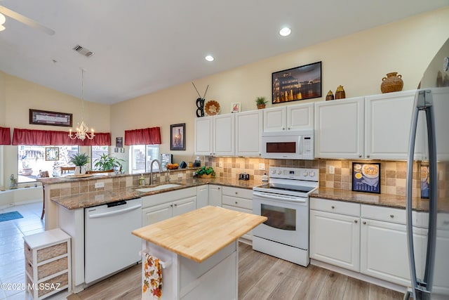 kitchen featuring pendant lighting, sink, white cabinets, kitchen peninsula, and white appliances