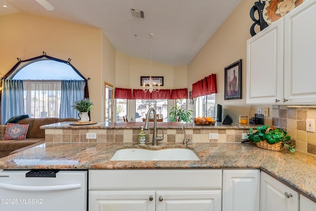 kitchen featuring lofted ceiling, sink, white cabinetry, light stone countertops, and a healthy amount of sunlight