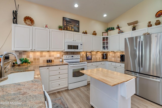 kitchen with vaulted ceiling, sink, white cabinets, and white appliances