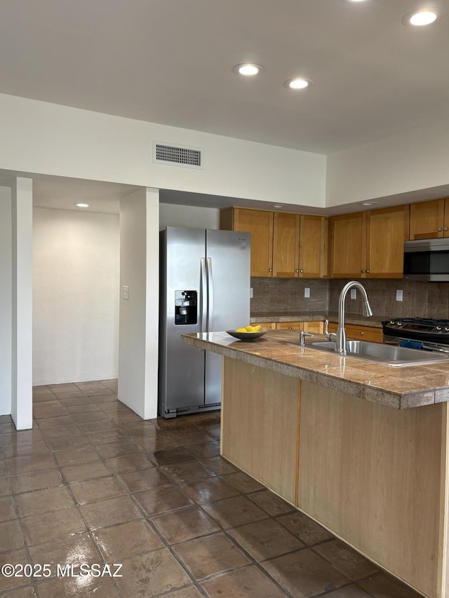 kitchen with appliances with stainless steel finishes, a kitchen island with sink, sink, and decorative backsplash