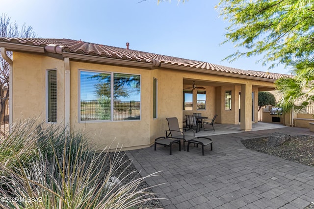 rear view of house featuring ceiling fan and a patio area