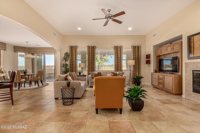 living room with a tile fireplace and ceiling fan