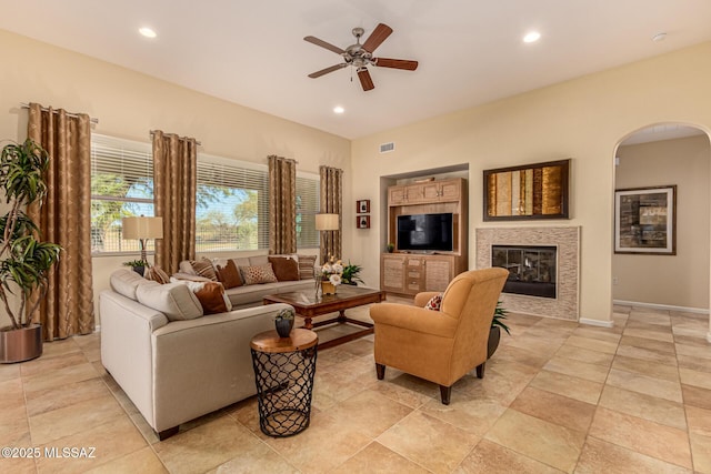 living room featuring ceiling fan and a tile fireplace