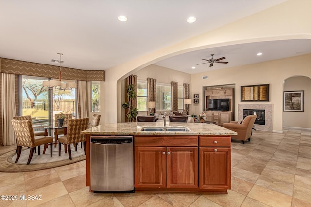 kitchen featuring pendant lighting, sink, light stone countertops, an island with sink, and stainless steel dishwasher