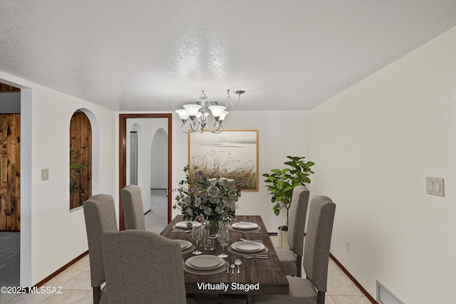 dining area with a textured ceiling, light tile patterned floors, and a notable chandelier