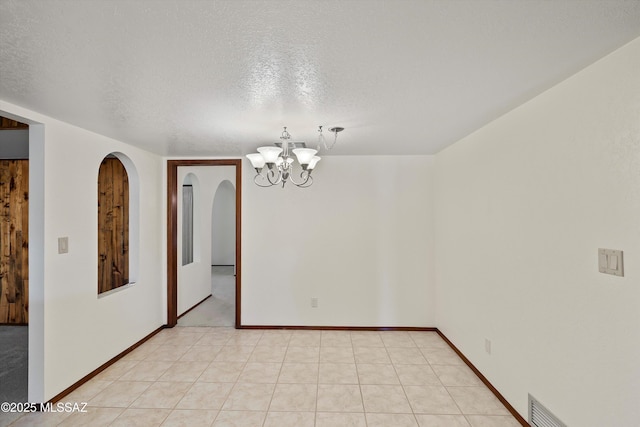 spare room featuring a textured ceiling and a notable chandelier