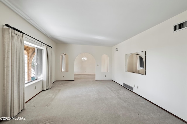 spare room with light carpet and a notable chandelier