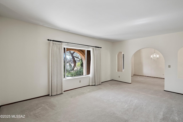 carpeted spare room with an inviting chandelier