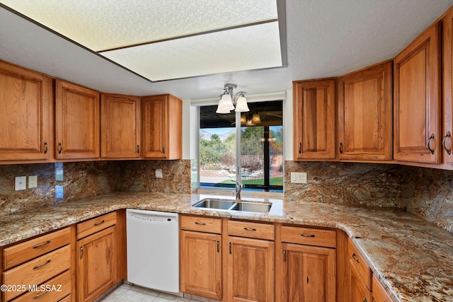 kitchen with sink, tasteful backsplash, light stone countertops, and white dishwasher