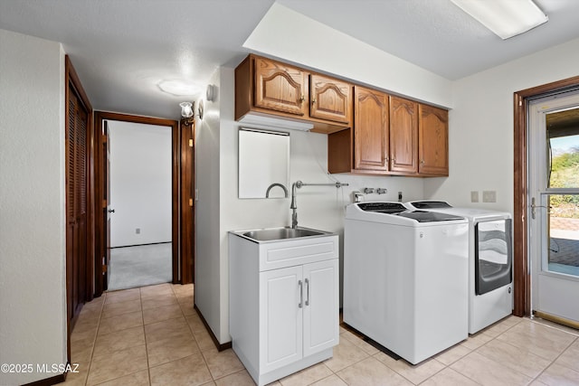 washroom with cabinets, sink, light tile patterned flooring, and washing machine and clothes dryer