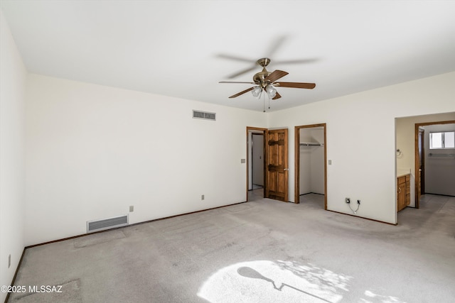 unfurnished bedroom with light carpet, ceiling fan, ensuite bath, a spacious closet, and a closet