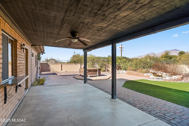 view of patio featuring a mountain view, a hot tub, and ceiling fan