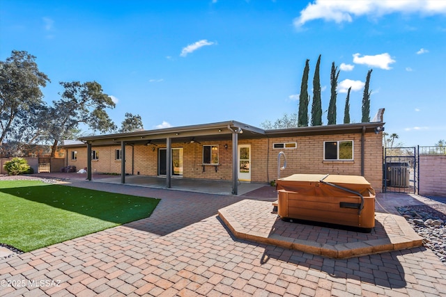 rear view of property with a patio area, a yard, a hot tub, and ceiling fan