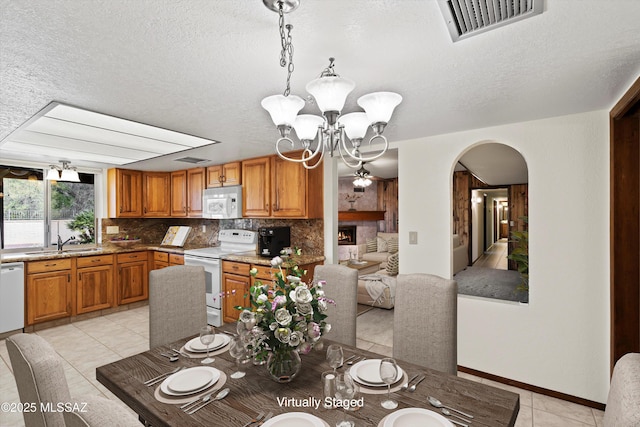 dining room with sink, an inviting chandelier, a textured ceiling, and light tile patterned floors