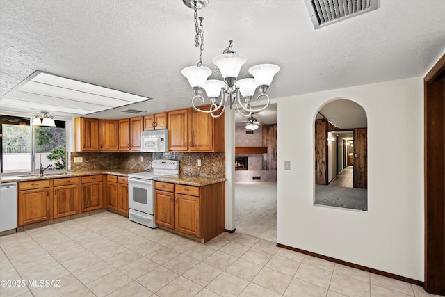 kitchen featuring white appliances, tasteful backsplash, sink, hanging light fixtures, and light stone counters