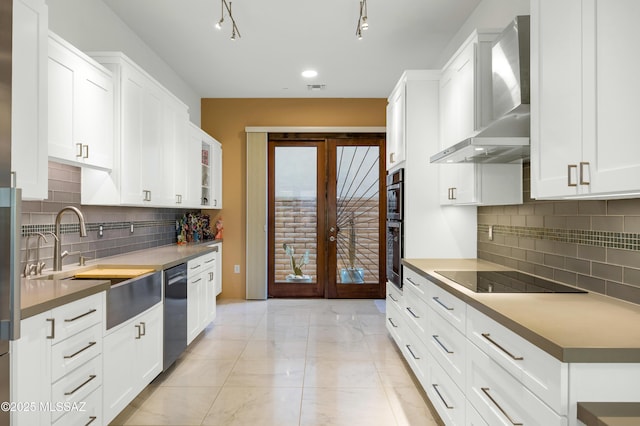 kitchen featuring wall chimney range hood, french doors, white cabinets, and appliances with stainless steel finishes