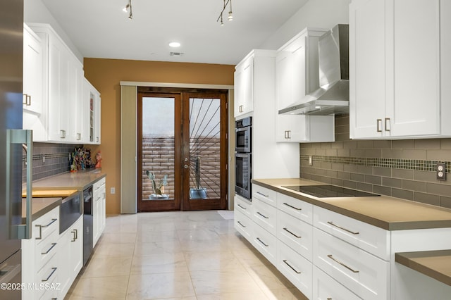 kitchen featuring black appliances, white cabinets, french doors, backsplash, and wall chimney exhaust hood