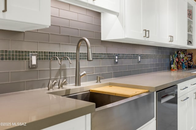 kitchen featuring white cabinets, stainless steel dishwasher, tasteful backsplash, and sink