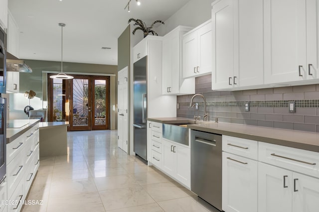 kitchen featuring appliances with stainless steel finishes, decorative light fixtures, white cabinetry, decorative backsplash, and sink