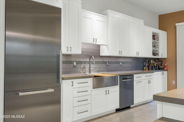 kitchen with decorative backsplash, white cabinets, stainless steel built in refrigerator, and light tile patterned floors