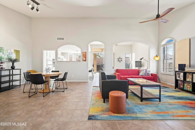 living area with tile patterned floors, arched walkways, visible vents, and ceiling fan