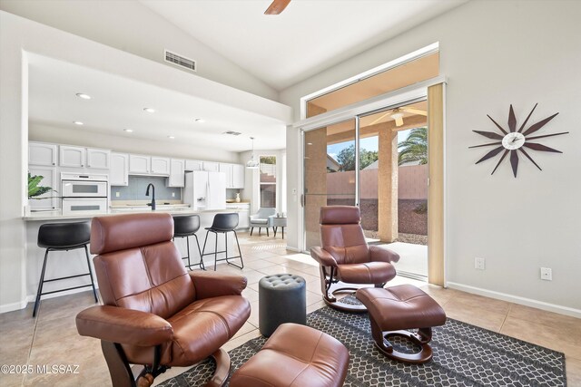 tiled living room featuring ceiling fan, sink, and lofted ceiling