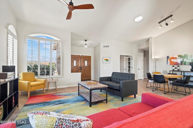 living room featuring visible vents, lofted ceiling, baseboards, and a ceiling fan