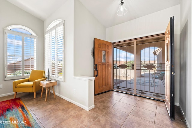 tiled foyer entrance with baseboards and lofted ceiling