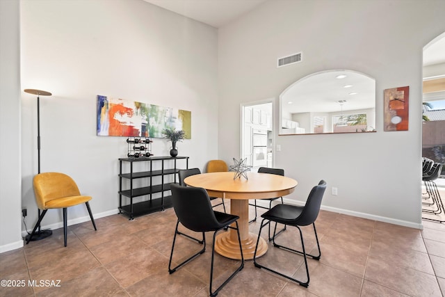 tiled dining room featuring a towering ceiling