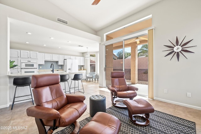 tiled living room featuring sink, ceiling fan, and lofted ceiling