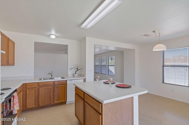 kitchen featuring white appliances, a kitchen island, a healthy amount of sunlight, sink, and hanging light fixtures