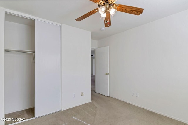 unfurnished bedroom featuring ceiling fan, light colored carpet, and a closet