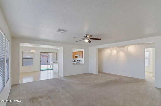 unfurnished living room featuring ceiling fan, light carpet, and a textured ceiling