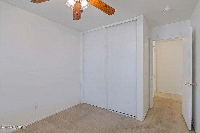 unfurnished bedroom with light carpet, a closet, and ceiling fan