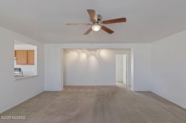 carpeted spare room with ceiling fan, sink, and a textured ceiling