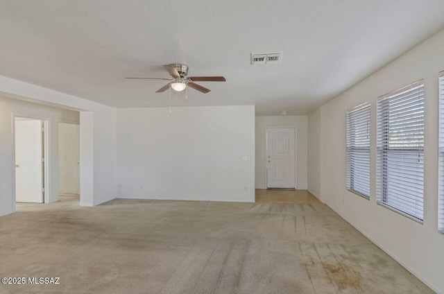 carpeted spare room with a textured ceiling and ceiling fan