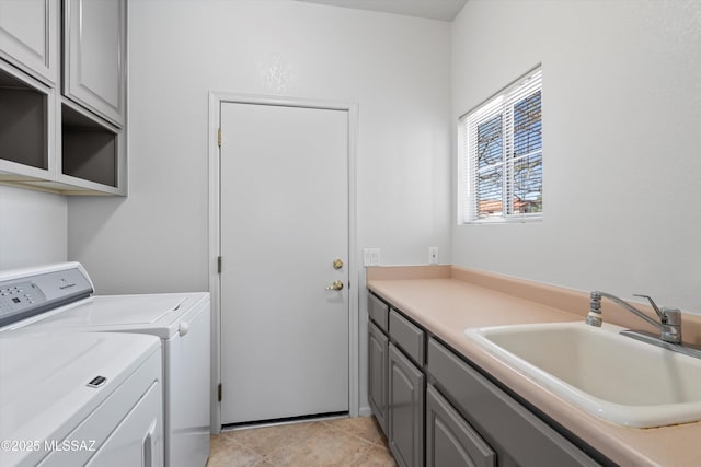 laundry room featuring cabinet space, light tile patterned floors, washing machine and dryer, and a sink