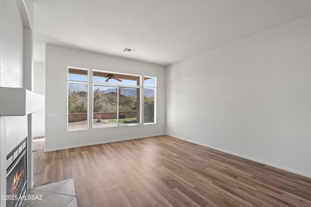 unfurnished living room featuring visible vents, baseboards, a ceiling fan, and wood finished floors