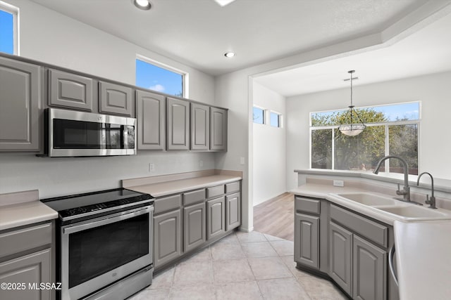 kitchen with a sink, stainless steel appliances, a wealth of natural light, and gray cabinets