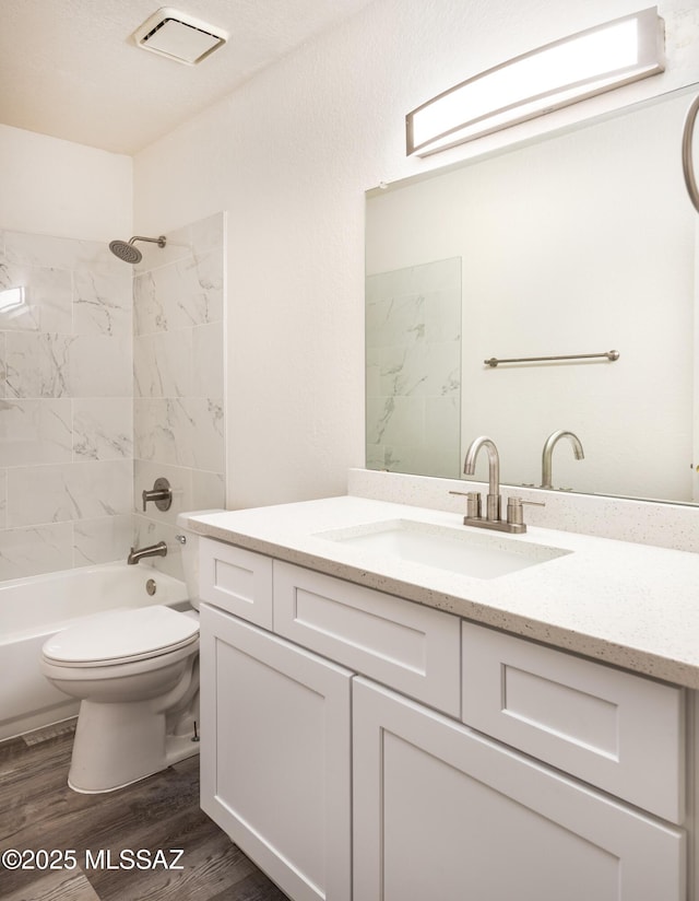 full bathroom with hardwood / wood-style flooring, vanity, toilet, and tiled shower / bath combo