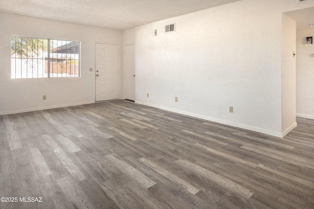 empty room with dark wood-type flooring and a textured ceiling