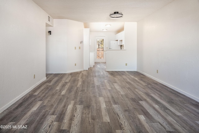 unfurnished living room with dark wood-type flooring and a textured ceiling