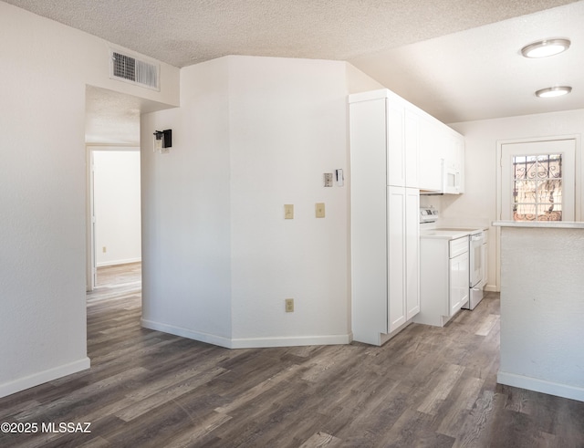 interior space with white cabinetry, white appliances, dark hardwood / wood-style flooring, and a textured ceiling