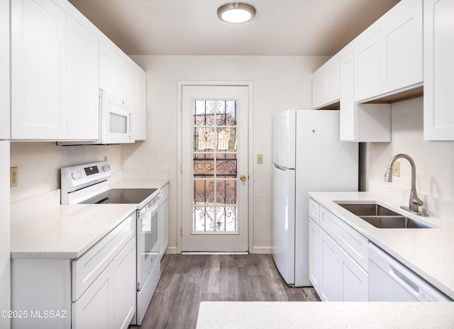 kitchen with sink, white appliances, wood-type flooring, and white cabinets