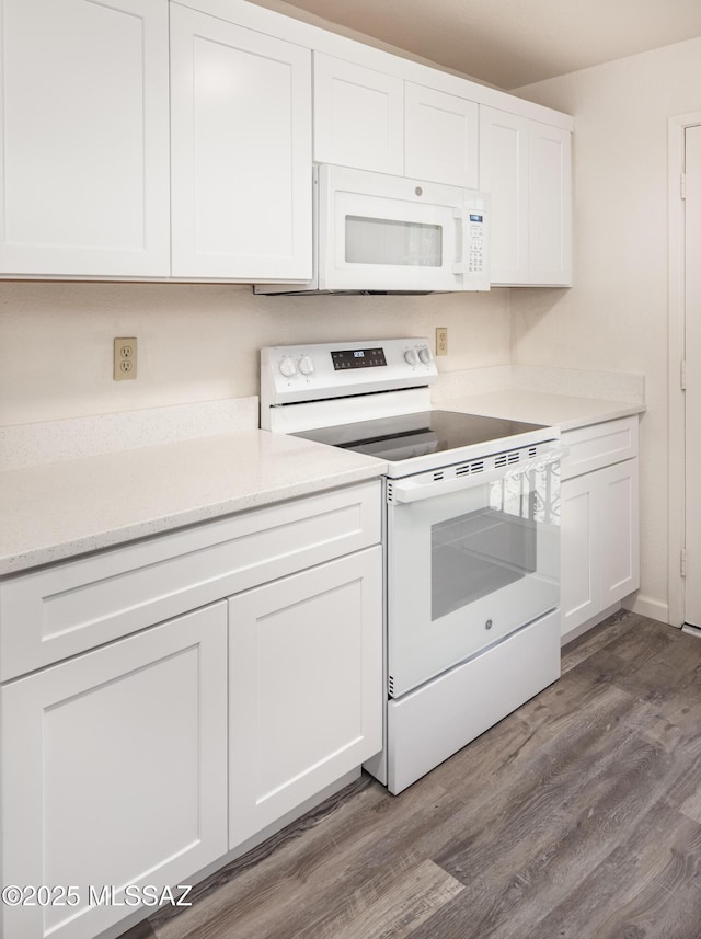 kitchen with hardwood / wood-style floors, white appliances, and white cabinets