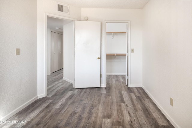 unfurnished bedroom with dark hardwood / wood-style floors and a closet