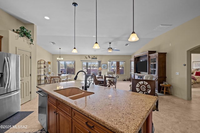 kitchen featuring sink, stainless steel appliances, hanging light fixtures, and a kitchen island with sink