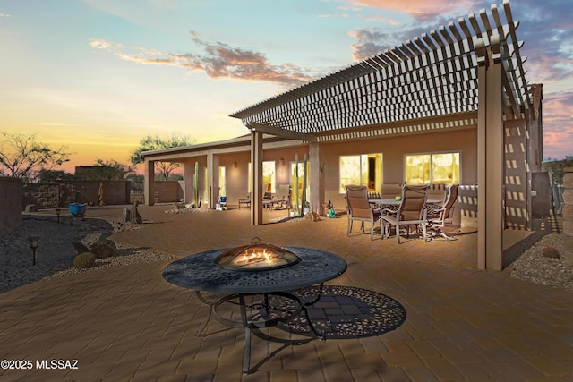 3534 E Sweet Grass Trl, Sahuarita, AZ 85629 - back of house at dusk with a fire pit, a patio area, outdoor dining area, and stucco siding