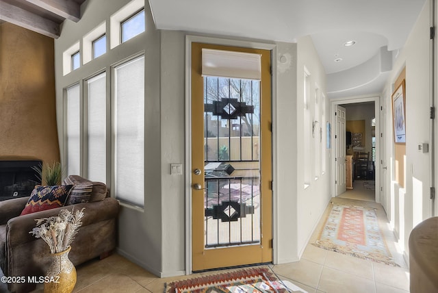 doorway with light tile patterned flooring, a healthy amount of sunlight, and beam ceiling