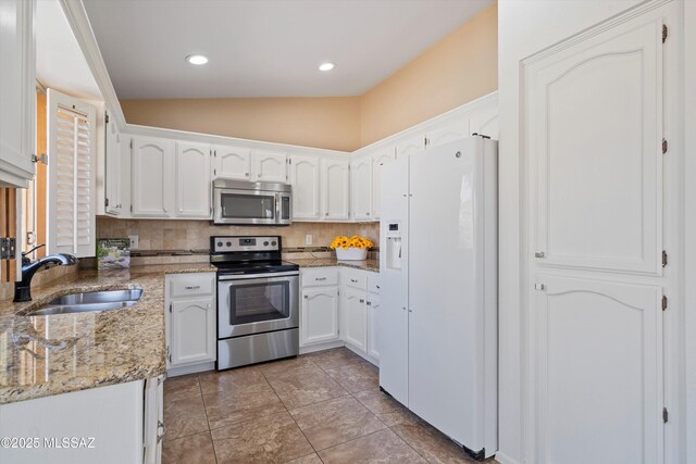 kitchen featuring sink, white cabinetry, dark stone countertops, stainless steel appliances, and tasteful backsplash